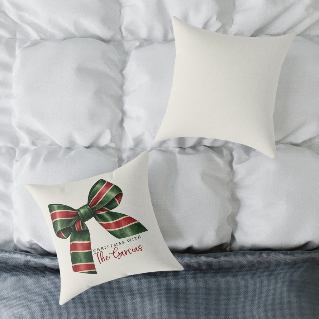 Front and back of the personalized striped ribbon bow family name Christmas pillow on a white bed