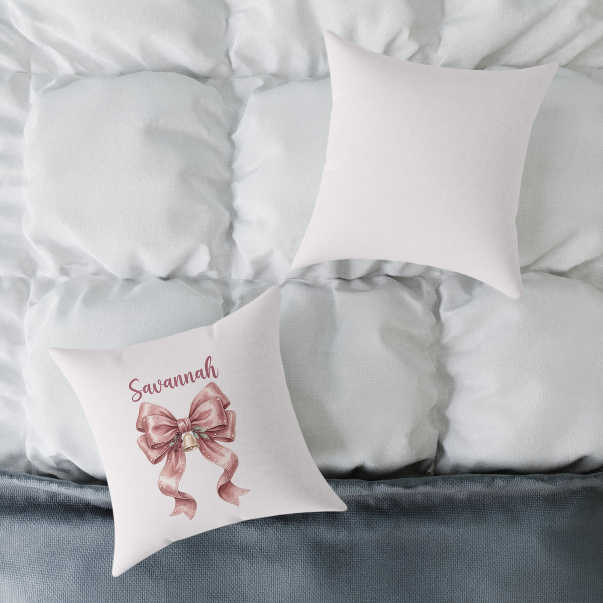 Front and back of the personalized blush velvet bow name pillow on a white bed
