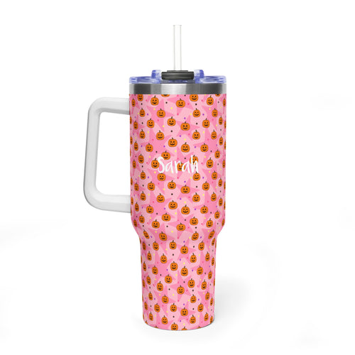 A pink handled tumbler with a repeating pattern of small orange jack-o'-lantern faces and white confetti, featuring a clear lid with a straw and the name 'Sarah' printed in white script on the front.