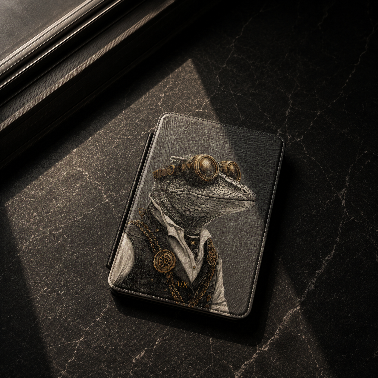 A black leather kindle case featuring a detailed illustration of a reptile wearing steampunk goggles, a white shirt, and gold chains, resting on a dark marble surface.