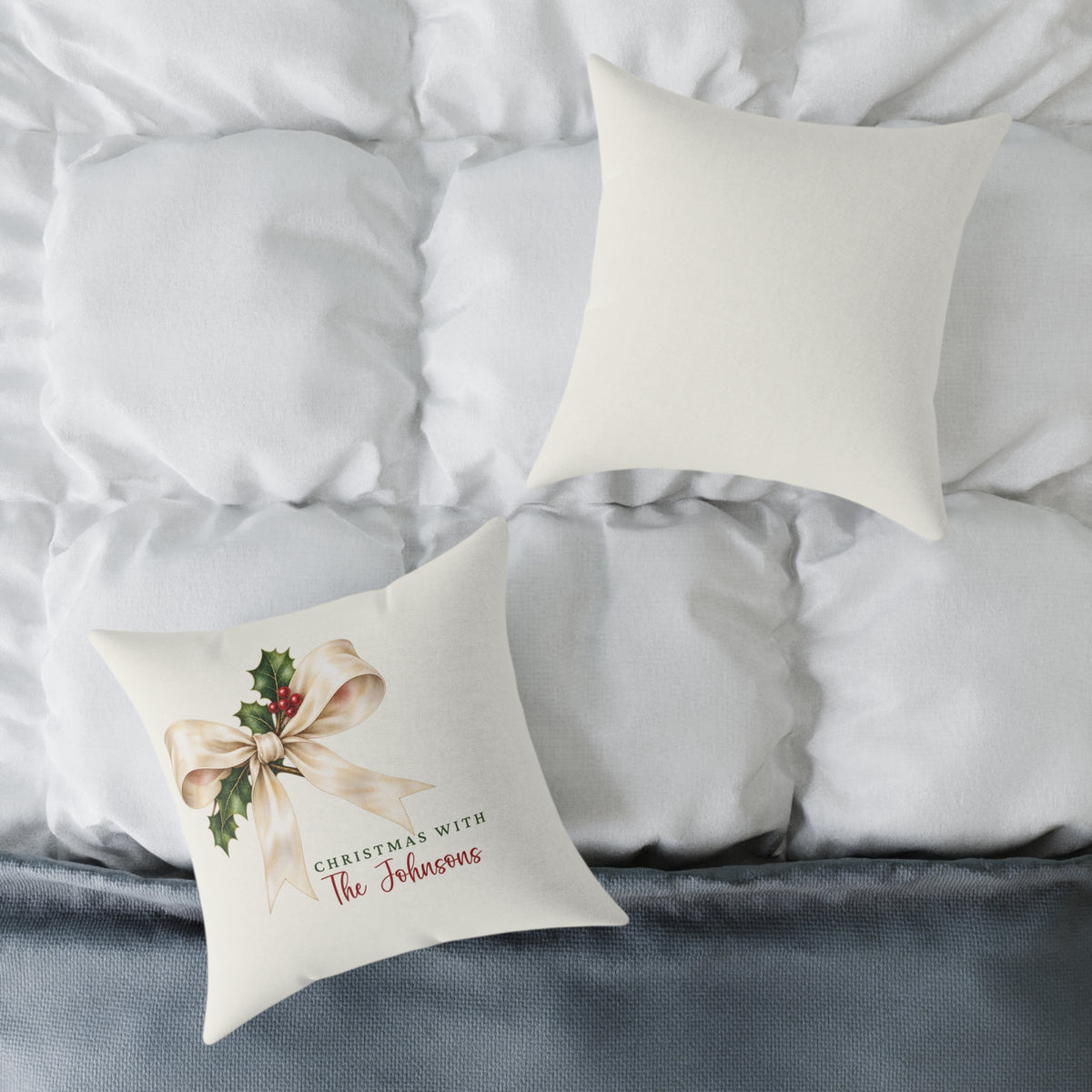 Front and back of the personalized cream bow and holly family name Christmas pillow on a white bed