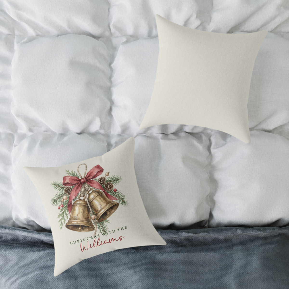 Front and back of the personalized brass bells family name Christmas pillow on a white bed