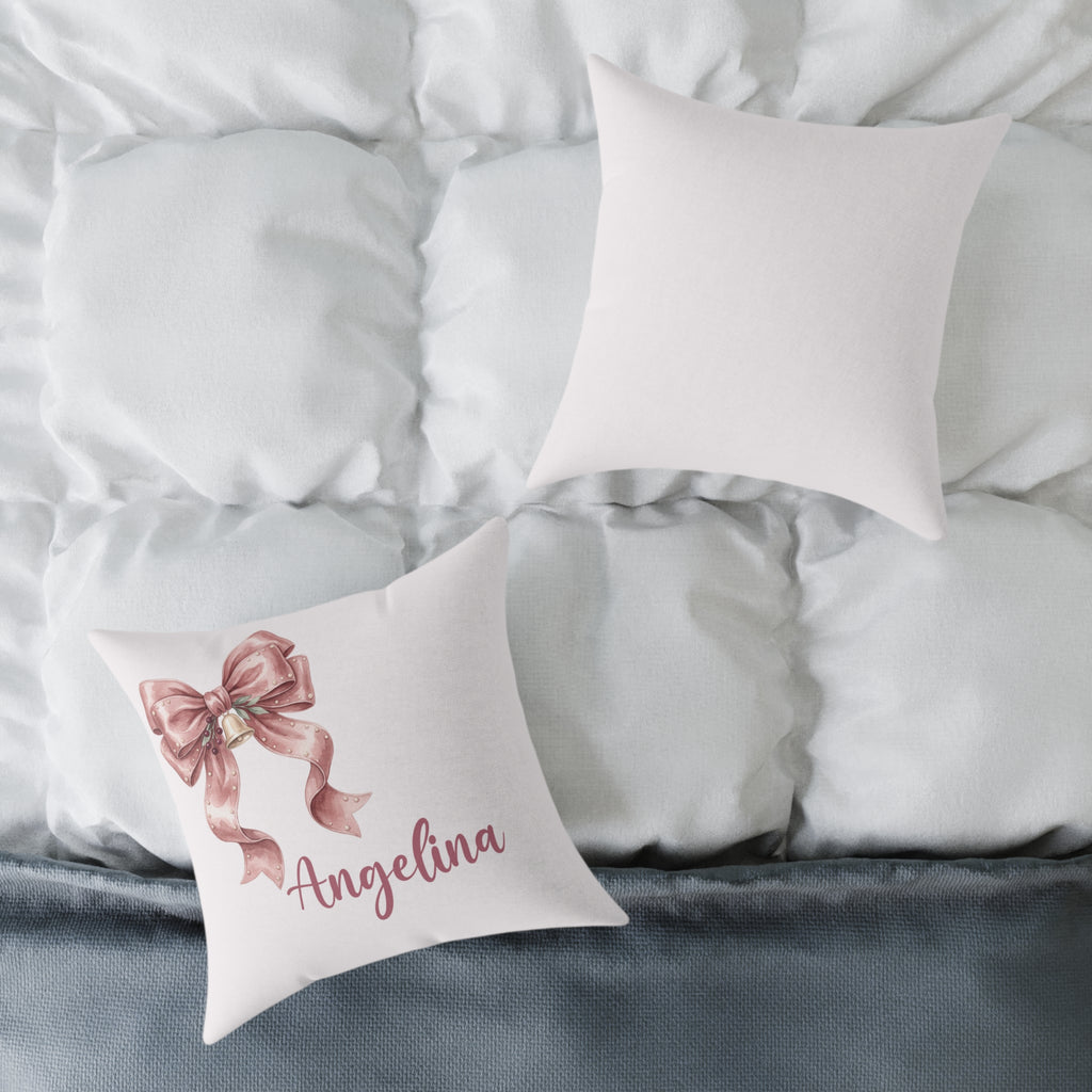 Front and back of the personalized pink ribbon bow name pillow on a white bed