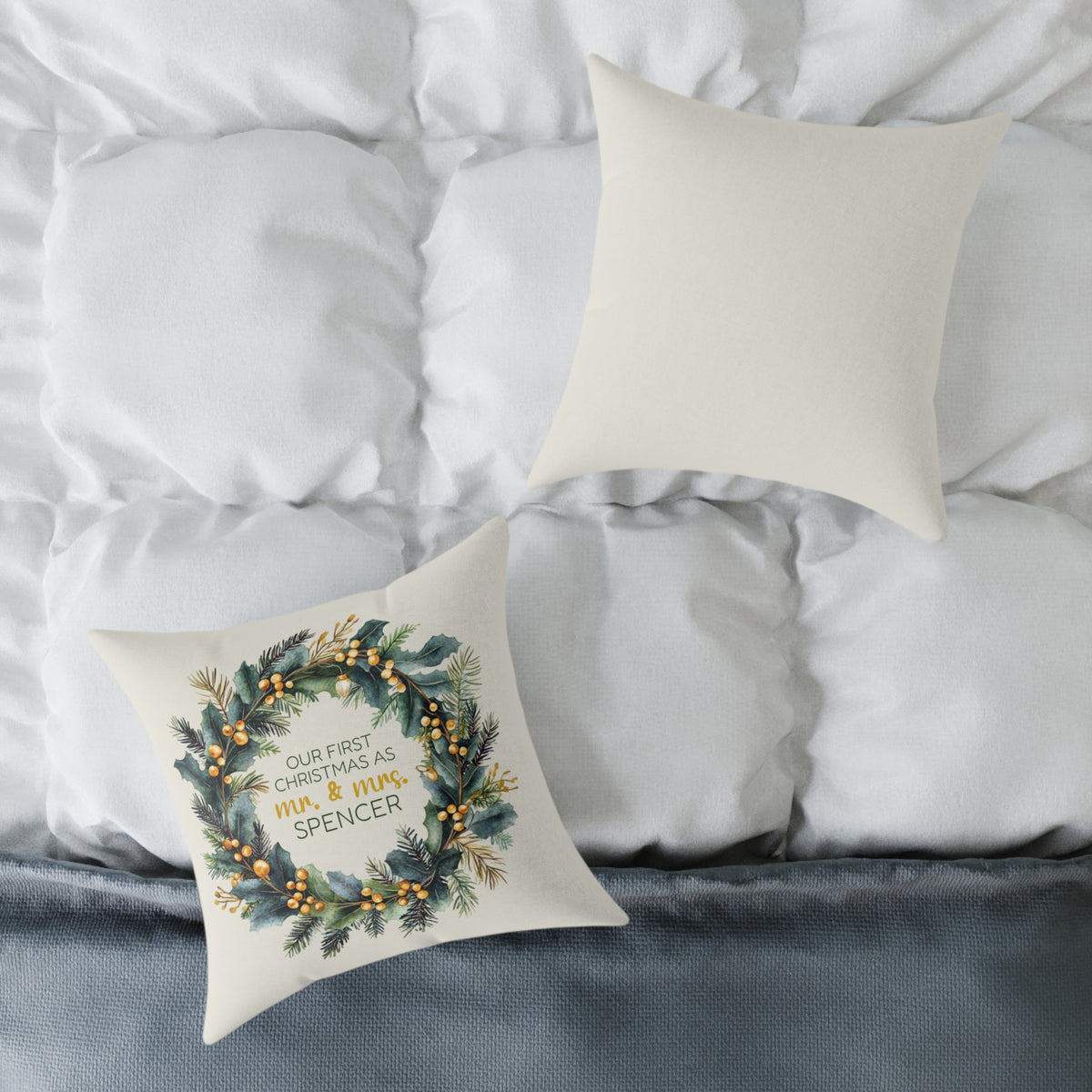 Front and back of the personalized first Christmas as Mr and Mrs gold berry wreath pillow on a white bed