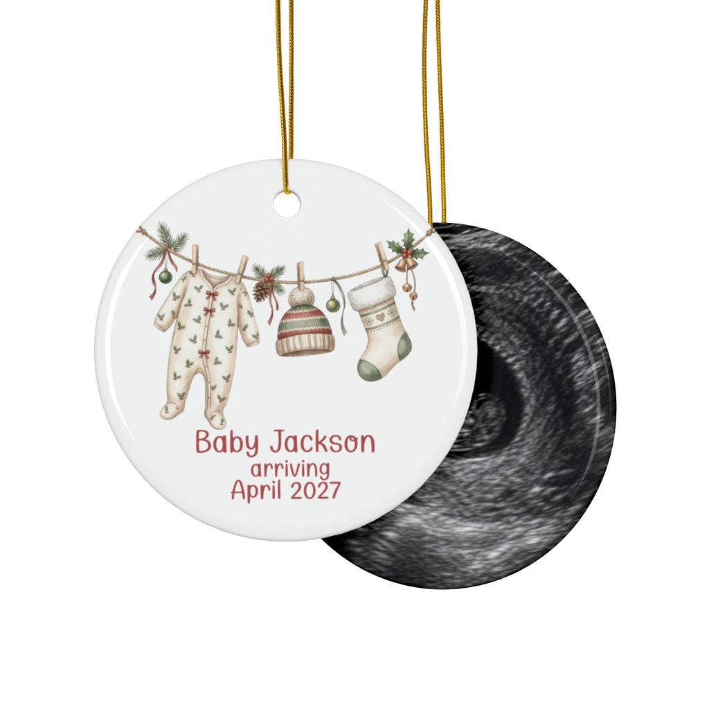 Double-sided baby arriving ornament with holly print sleeper, knit hat and stocking on the front and an ultrasound photo on the back
