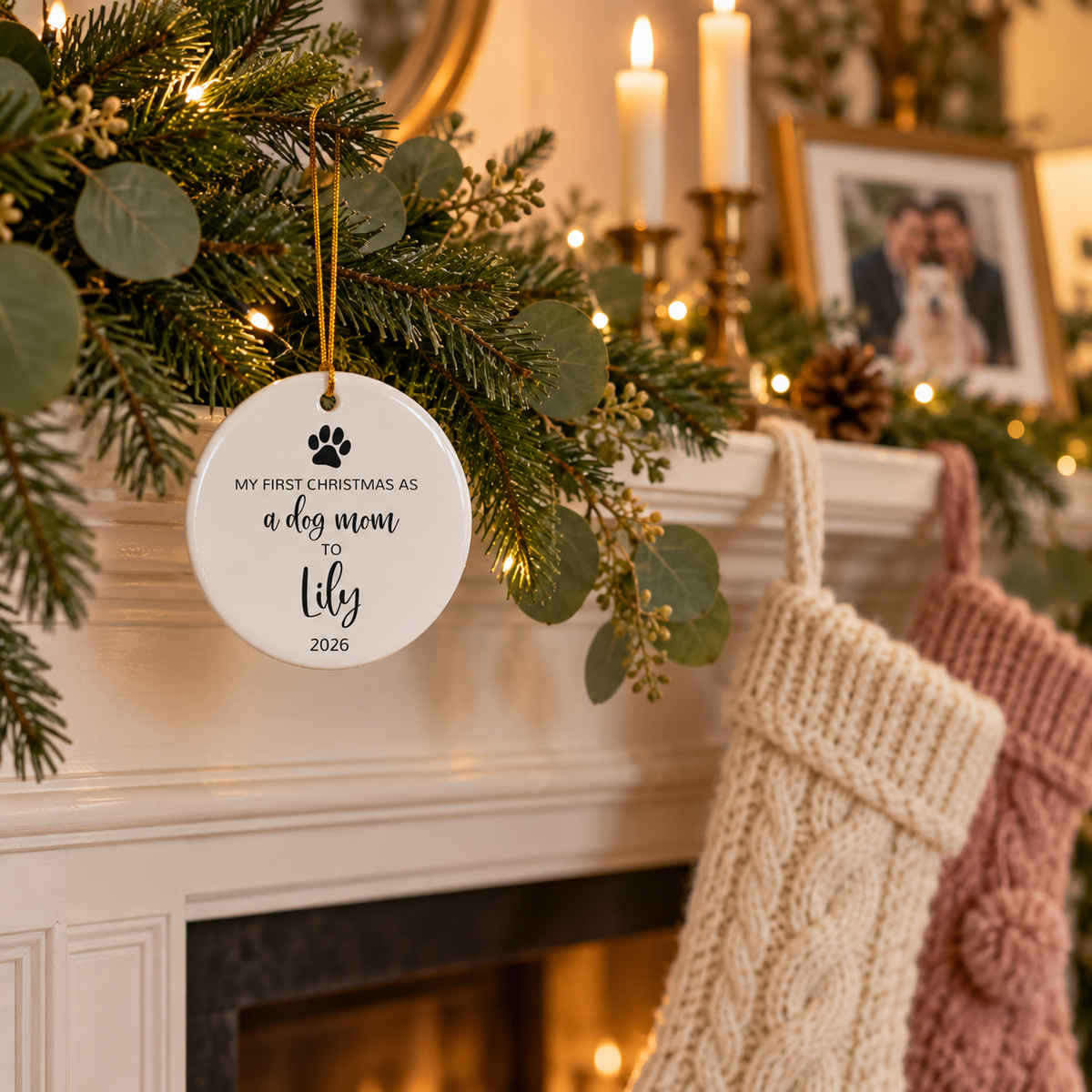 Personalized dog mom first Christmas ornament with paw print and black script name on a fireplace garland with stockings