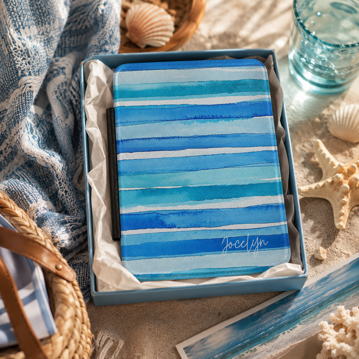 Personalized blue watercolor stripes horizontal Kindle case shown in a gift setting